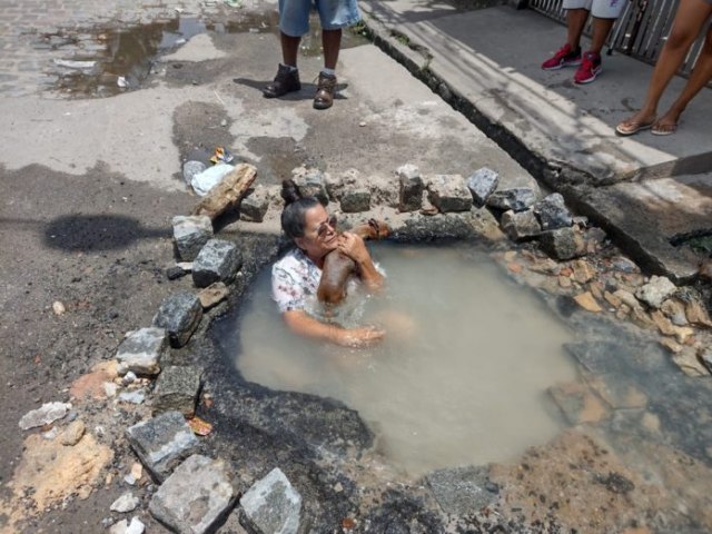 Sem gua na torneira, moradora do Grande Recife toma banho em cratera na rua para protestar contra vazamento